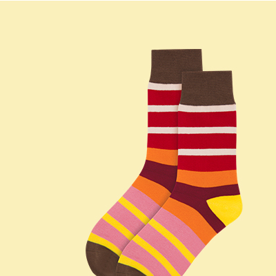 Zwei gestreifte Socken liegen übereinander, mit braunem Bündchen, roten und weißen Streifen oben und gelb-rosa Streifen unten. Der Hintergrund ist gelblich.