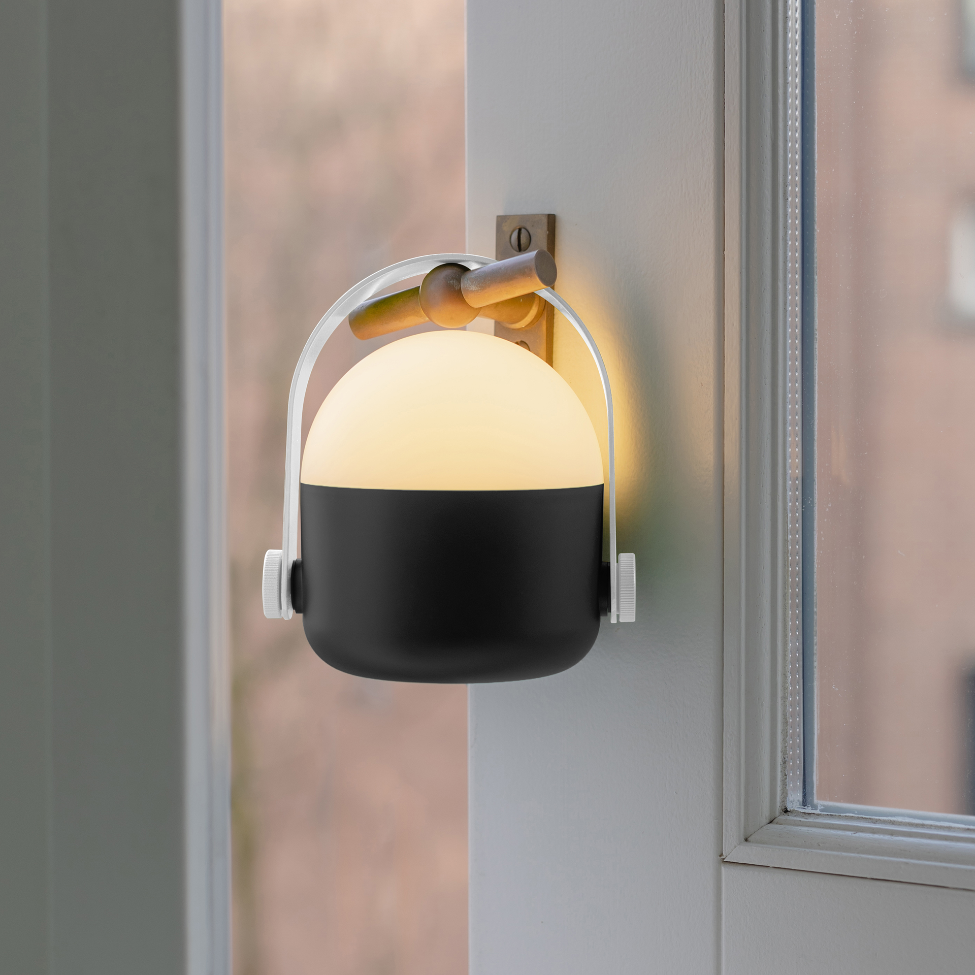 Schwarze, runde LED-Leuchte mit weißem Griff und Drehknopf. Die Lampe ist beleuchtet und strahlt ein warmes Licht aus.