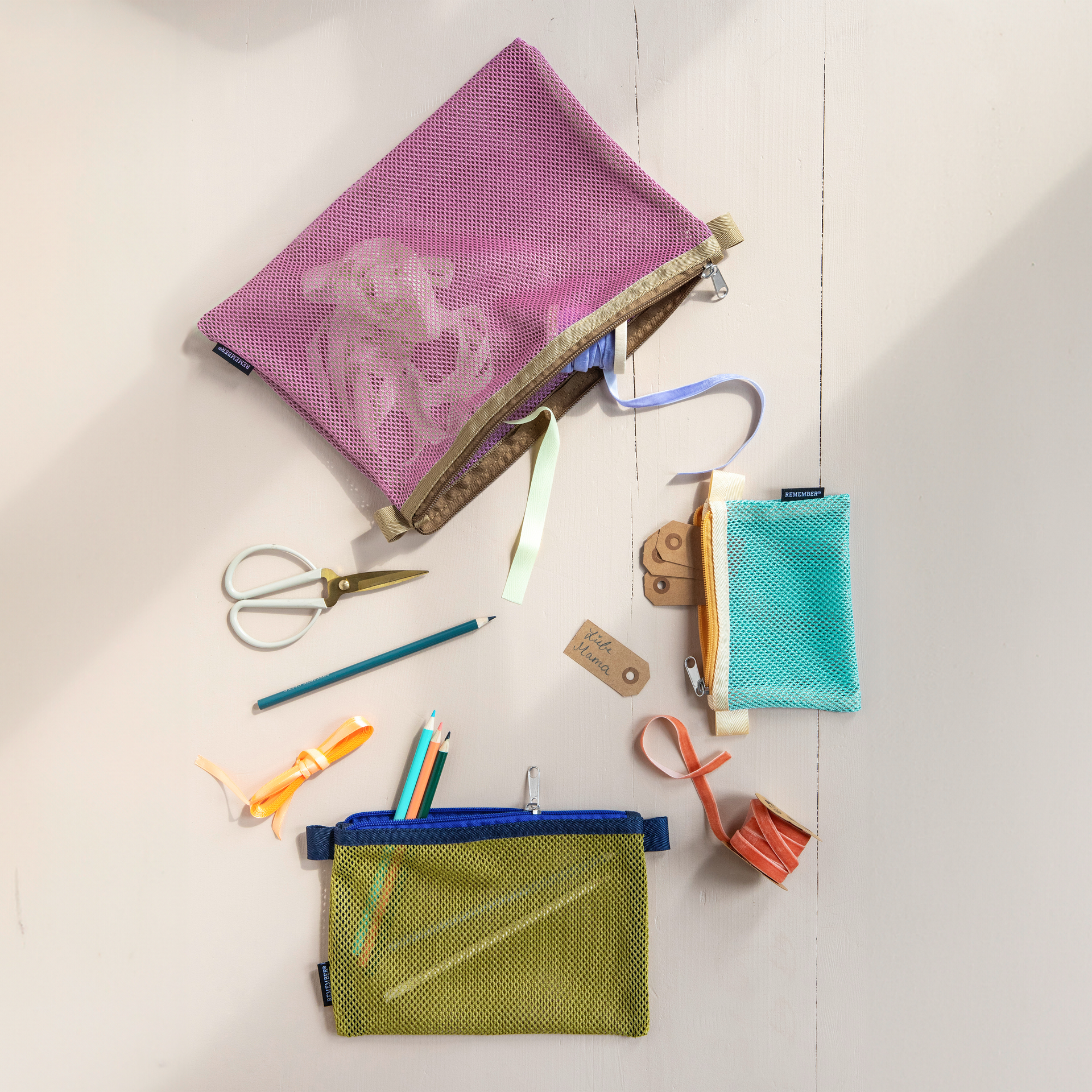 Ein 3er Set Mesh Bags 'Jordy' in Lila, Olive und Türkis, jeweils mit farblich passendem Reißverschluss und Einfassung.