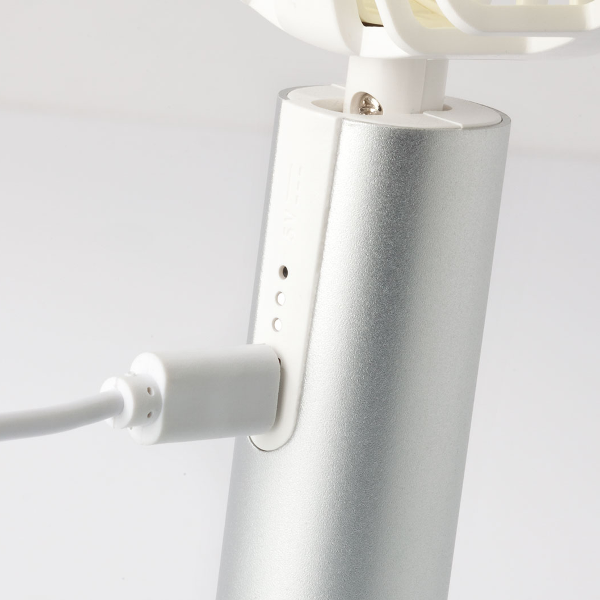 Detailaufnahme vom Ventilator Flow in Silber. Ein USB-Kabel ist an den silbernen Ventilator angeschlossen, daneben eine Akku-Ladestandanzeige.