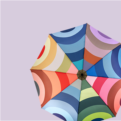 Produktansicht eines geöffneten Regenschirms mit bunten, konzentrischen Halbkreisen auf helllila Hintergrund.