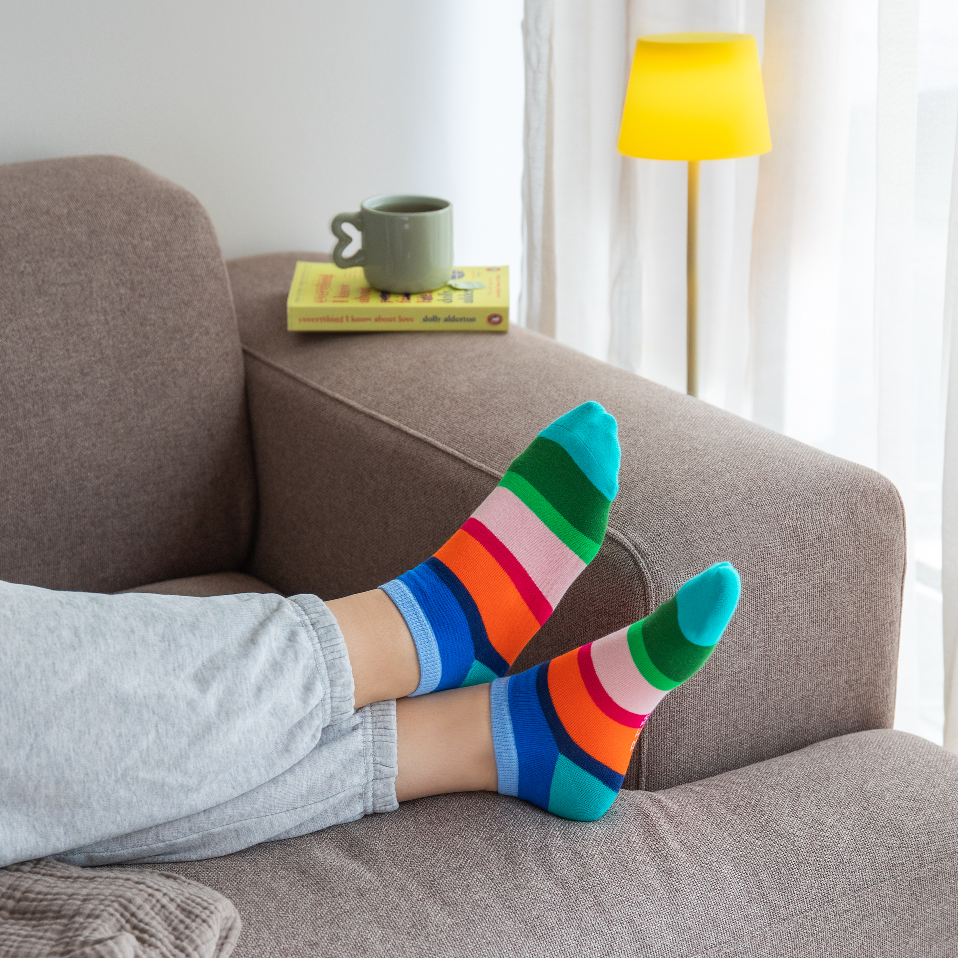 Drei Paar Sneakersocken, jedes mit bunten, horizontalen Streifen, liegen nebeneinander. Die Socken haben unterschiedliche Farbkombinationen.