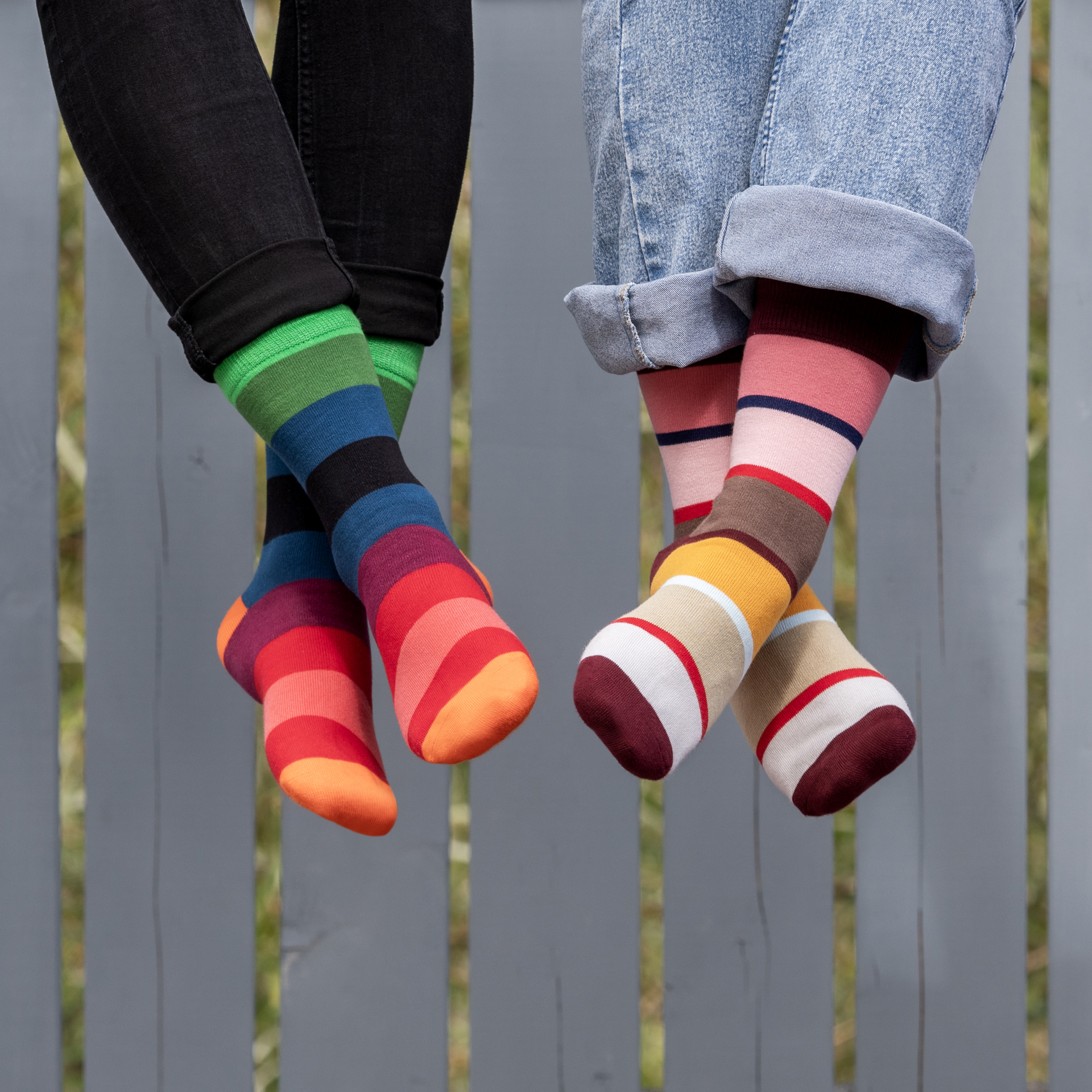 Zwei Socken, Größe 36-41, mit bunten, horizontalen Streifen in Grün, Blau, Schwarz, Lila, Pink und Orange auf weißem Hintergrund.