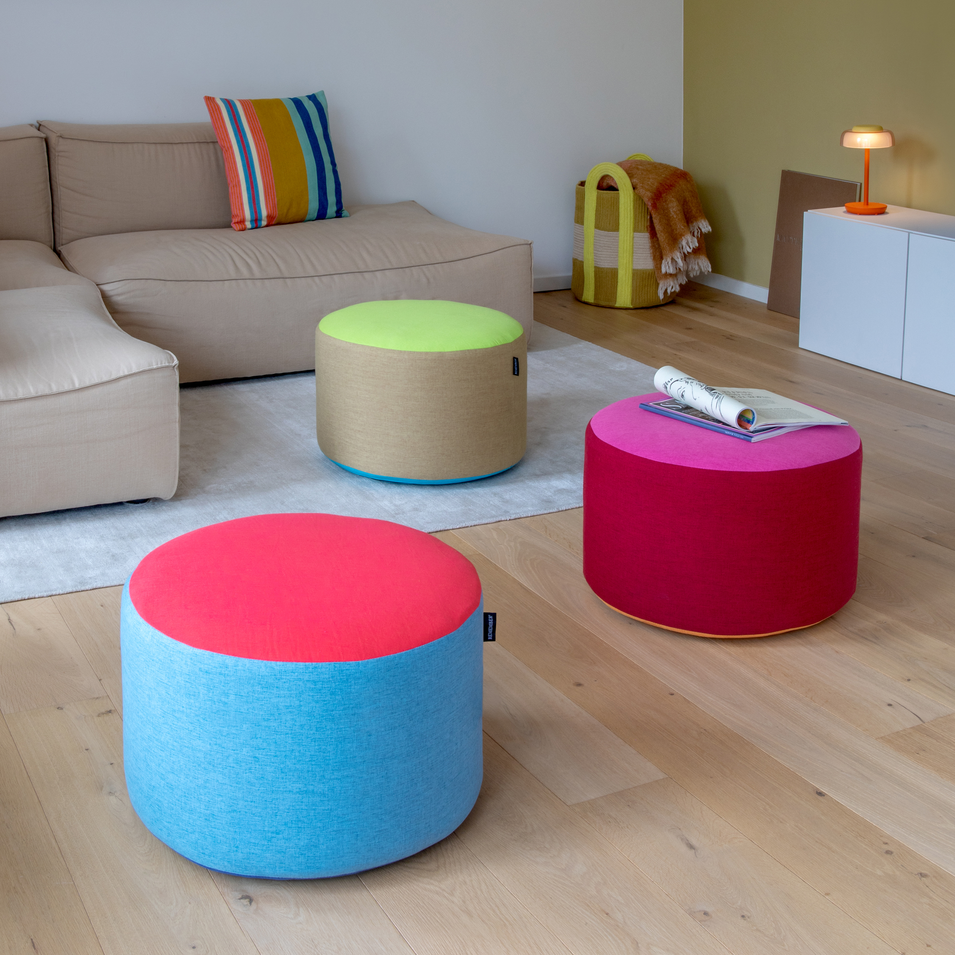 Pouf rond Pepe avec revêtement textile tricolore. Dessus rouge corail vif, parties latérales cylindriques bleu ciel, bord inférieur bleu plus foncé. Une touche de couleur pour s'asseoir et se détendre.