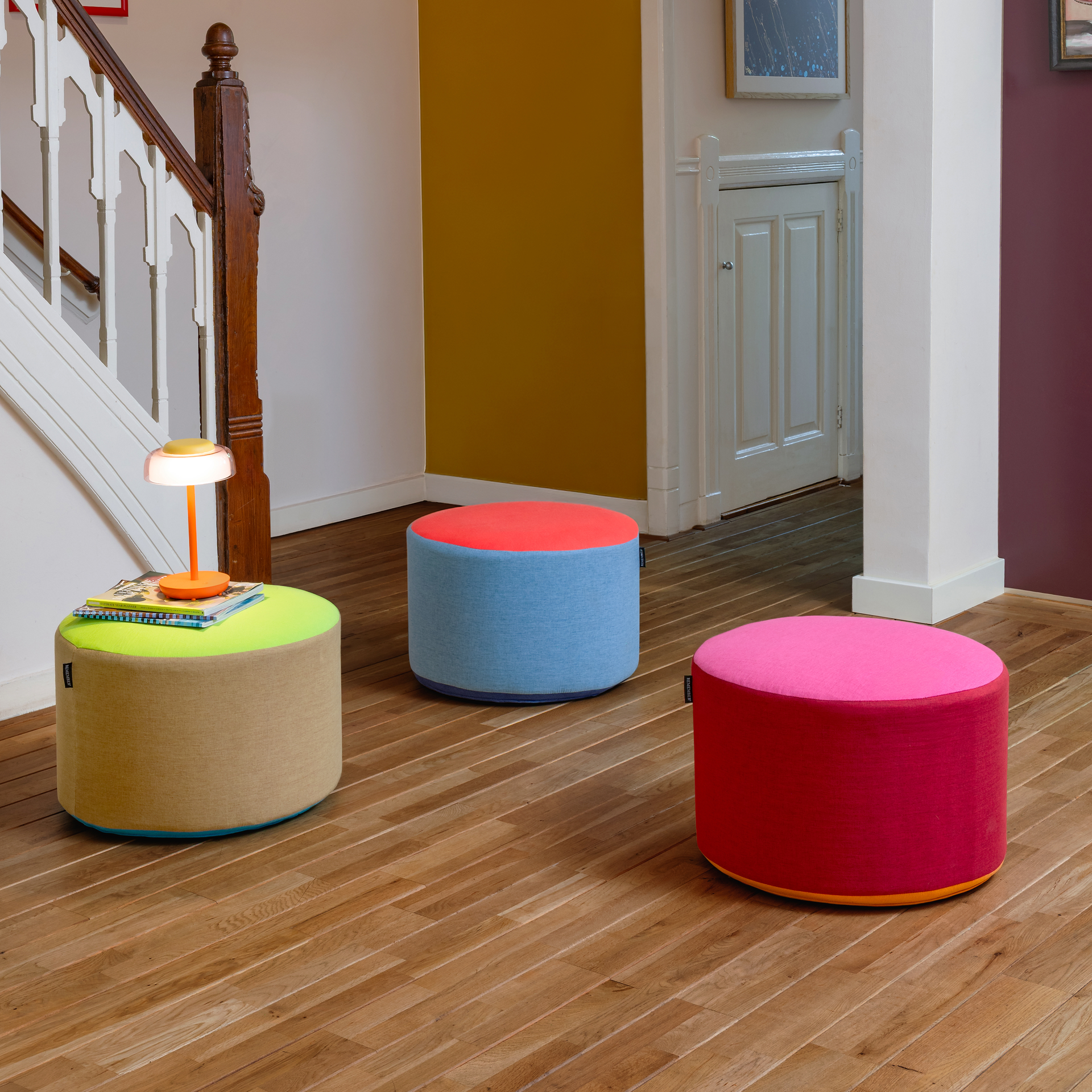 Le pouf rond Pepe berry est recouvert d'un tissu tricolore : rose vif sur le dessus, teinte baie plus foncée sur les côtés. Une fine bande orange sur le bord inférieur vient parachever le design. À utiliser comme siège ou comme surface de rangement.