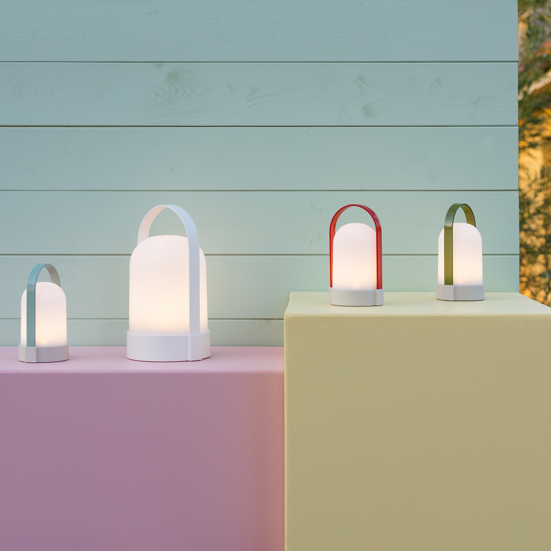Weiße, leuchtende URI Lampe mit einem Tragebügel, die auf einer ebenen Fläche steht und warmweißes Licht ausstrahlt.