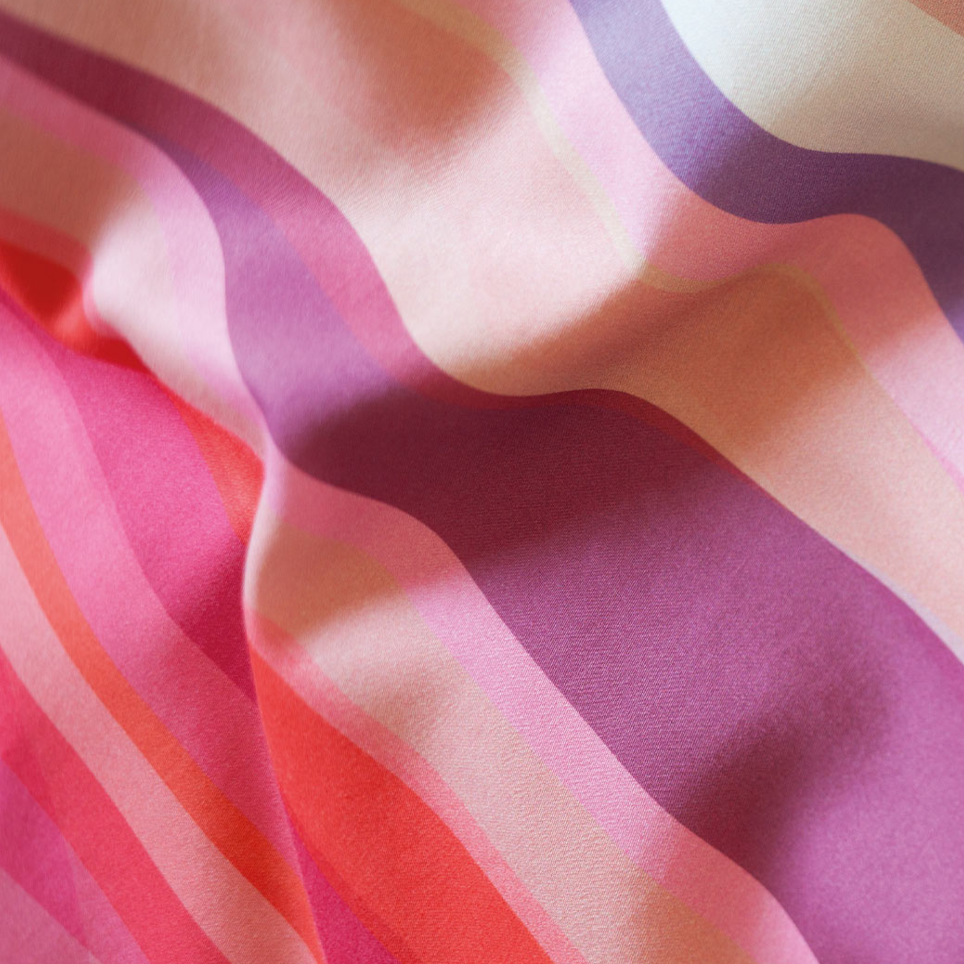 Nahaufnahme von gewellter Bettwäsche 'Mateo' mit wellenförmigen Streifen in Pink-, Rosa- und Lilatönen.