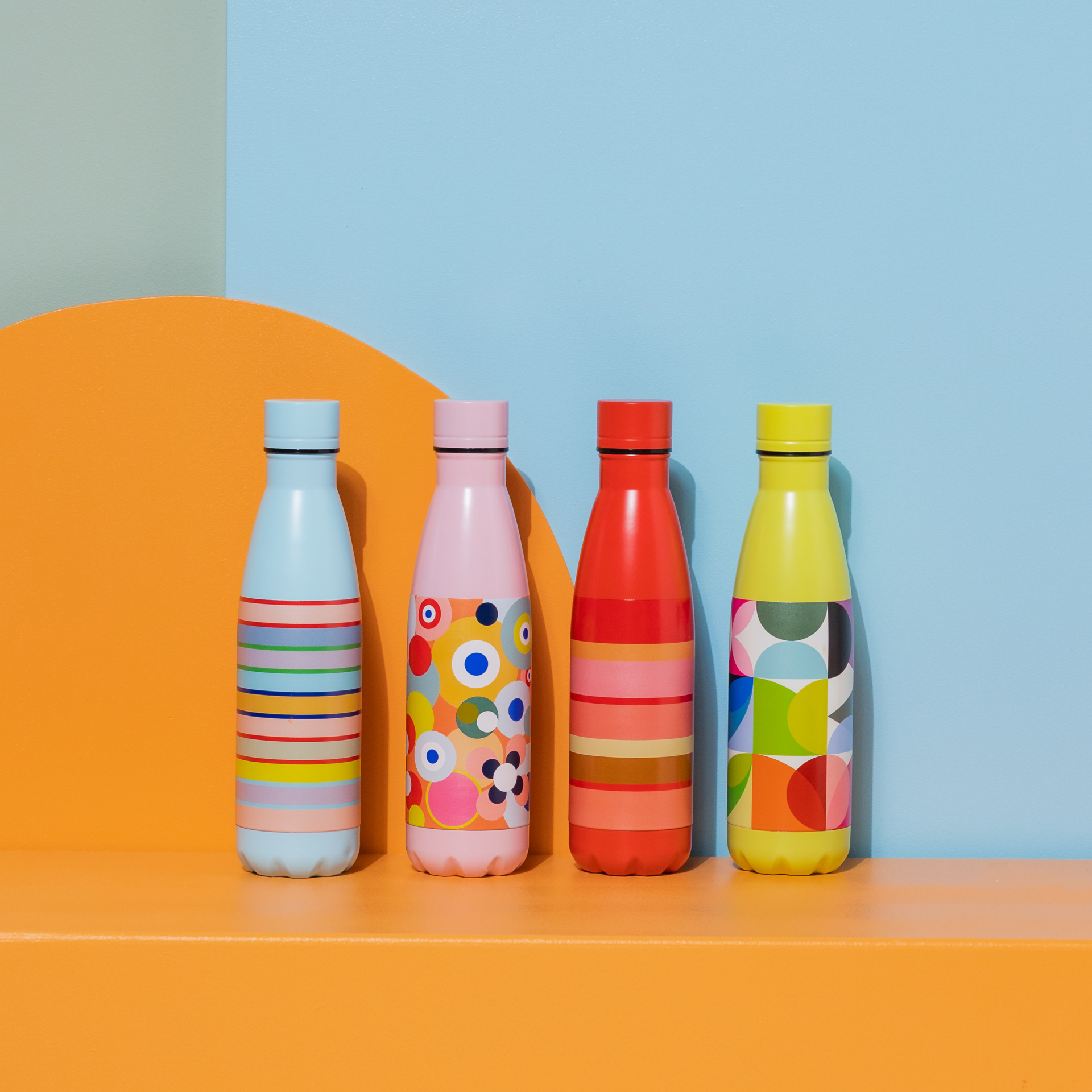 Schmale, rote Edelstahl-Trinkflasche mit bunten Streifen in Rosa-, Beige- und Orangetönen. Links daneben blaues Feld mit der Zahl 30 in bunten Streifen.