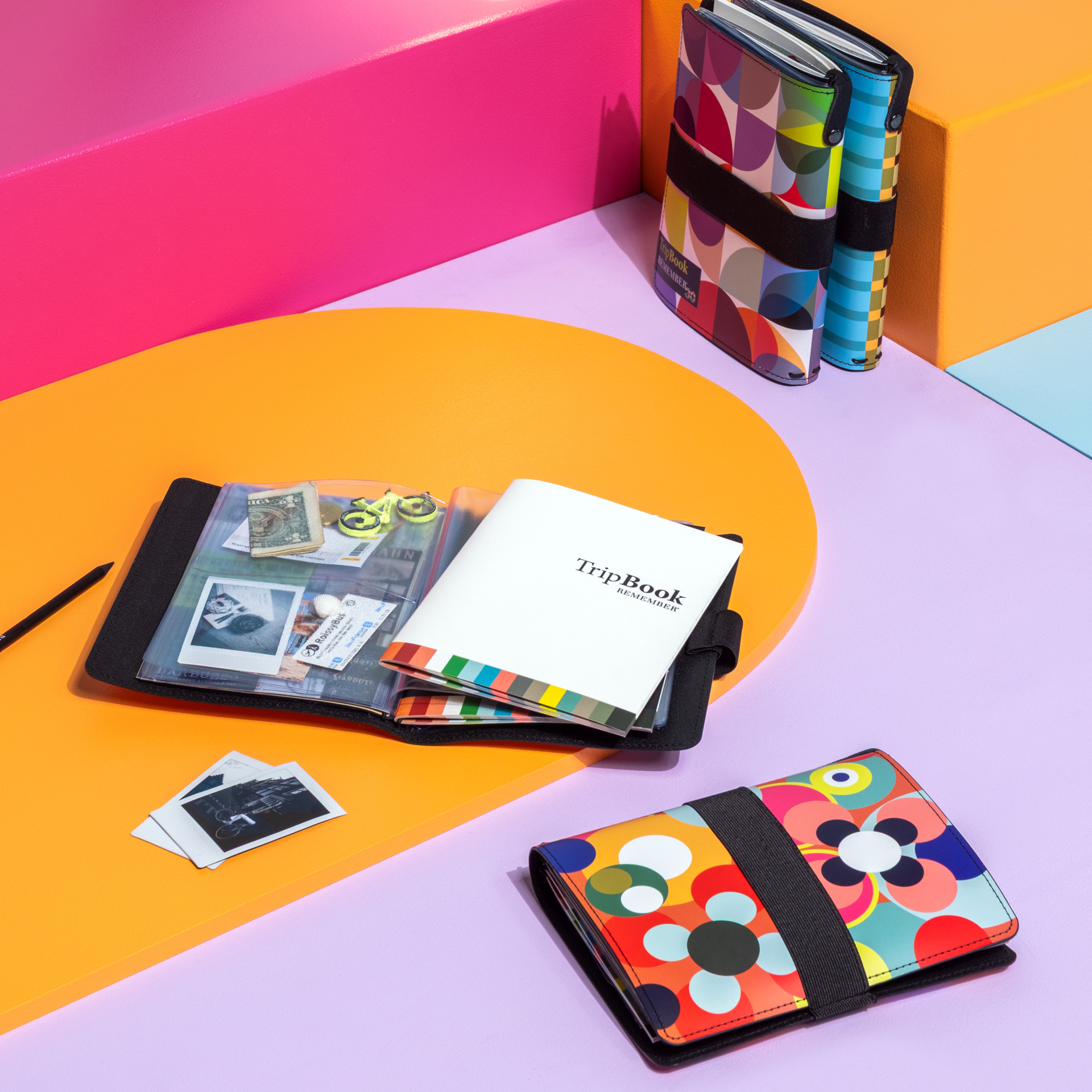 Quadratisches TripBook Sushi mit bunten Kreisen, schwarzem Gummiband und „30“-Logo.