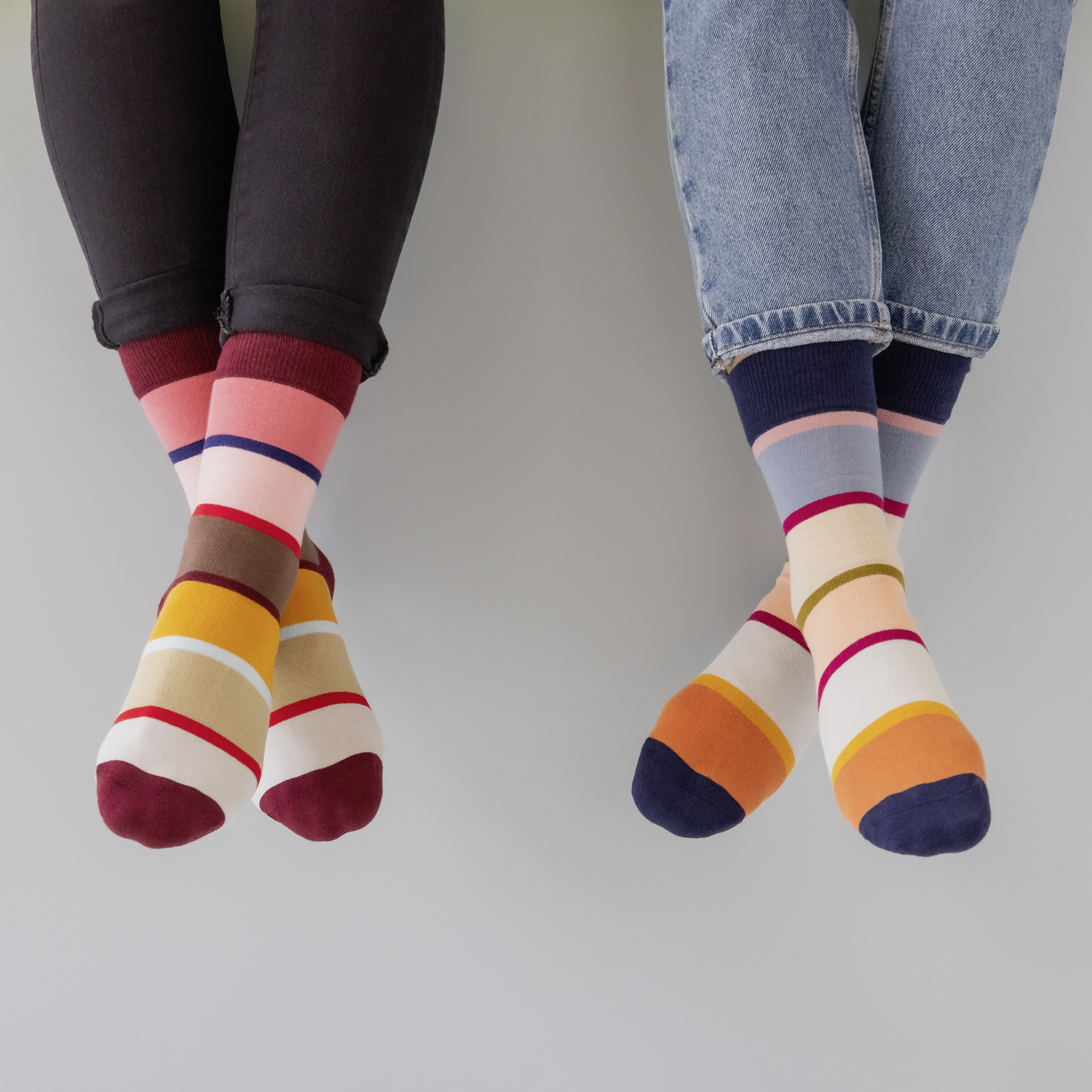 Zwei bunte Socken Modell 45, Größe 41-46, gestreift in den Farben Rot, Braun, Grün, Grau, Blau und Türkis, auf weißem Hintergrund.