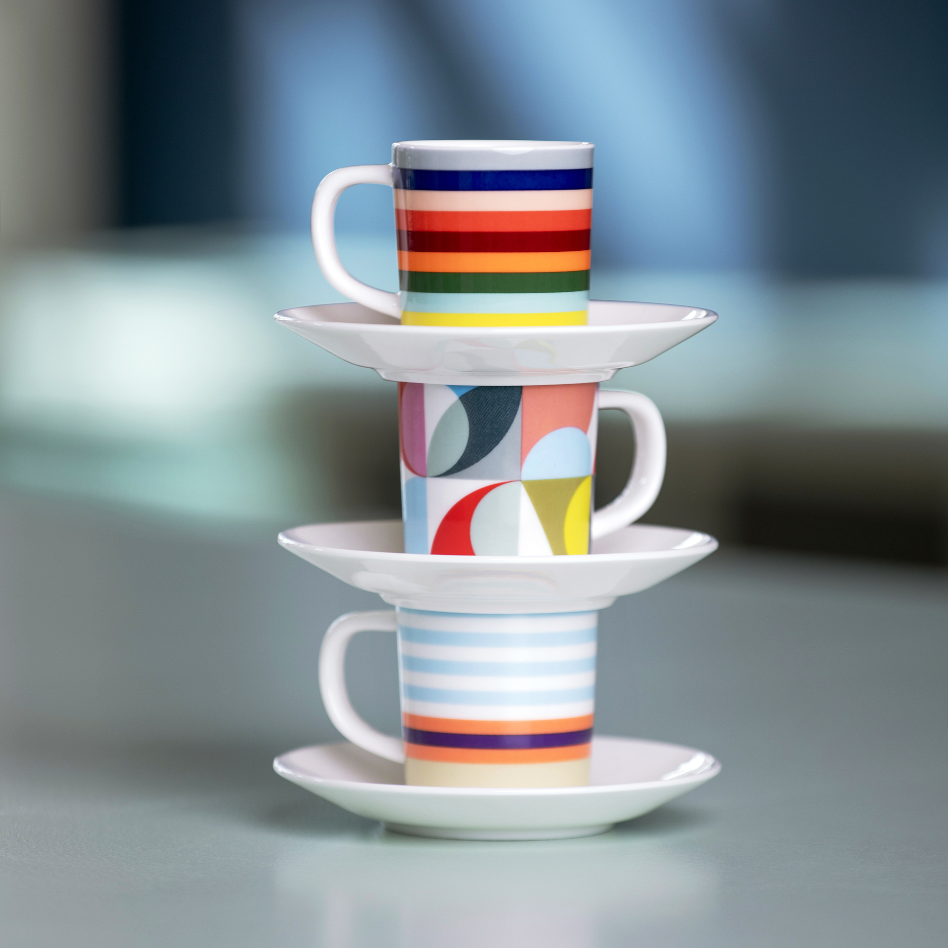 Drei 'Solena' Espressotassen mit Unterteller im Stack. Die Tassen sind mit farbigen Streifen und Mustern verziert.