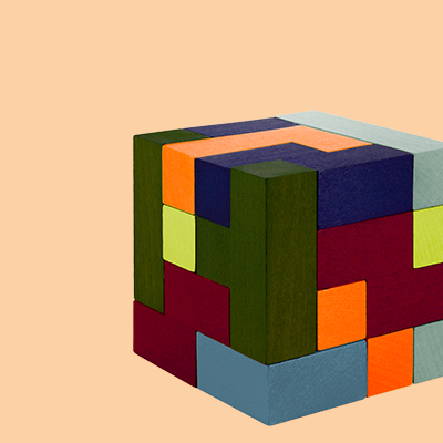 Ein farbenfroher Würfel aus Holzpuzzles, auf hell-orangenem Grund. Die Farben sind unter anderem orange, dunkelblau, grün und weinrot.