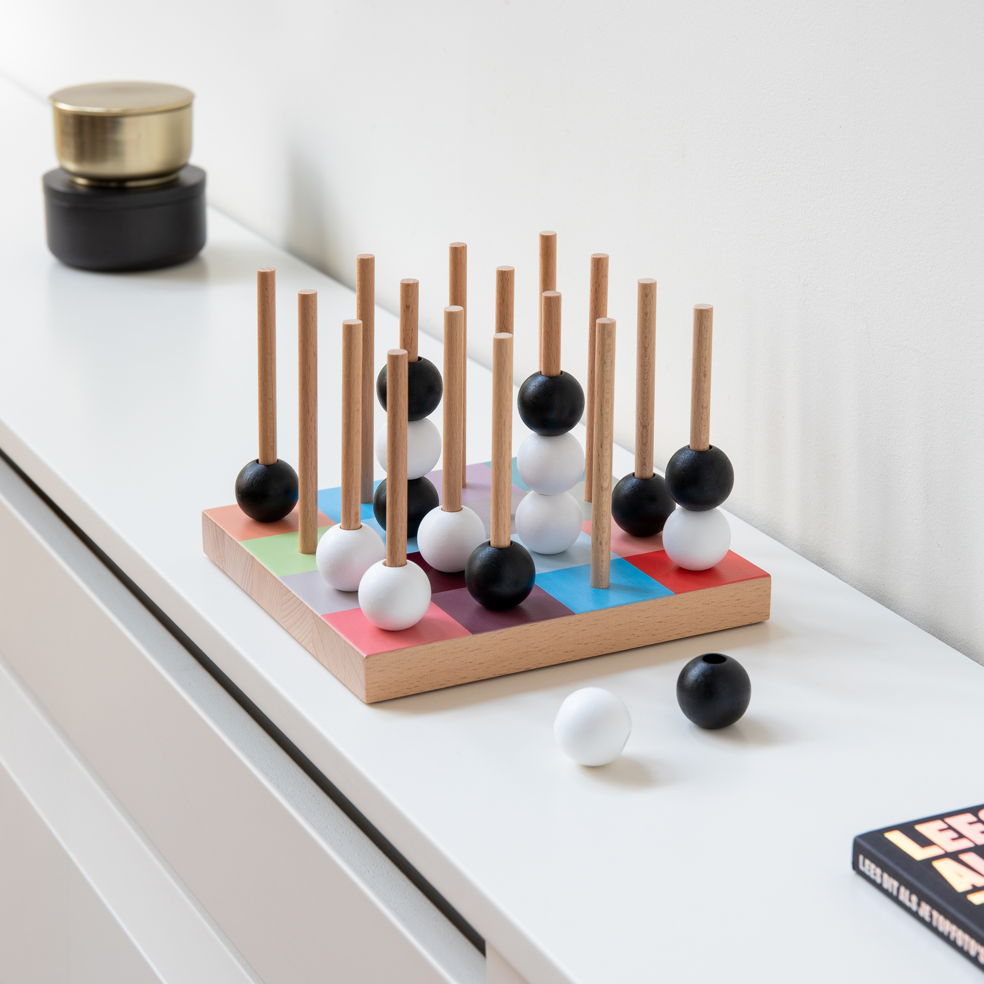 Detailaufnahme des SOGO-Brettspiels mit Holzstäben und schwarzen sowie weißen Kugeln auf einem farbigen Spielbrett.