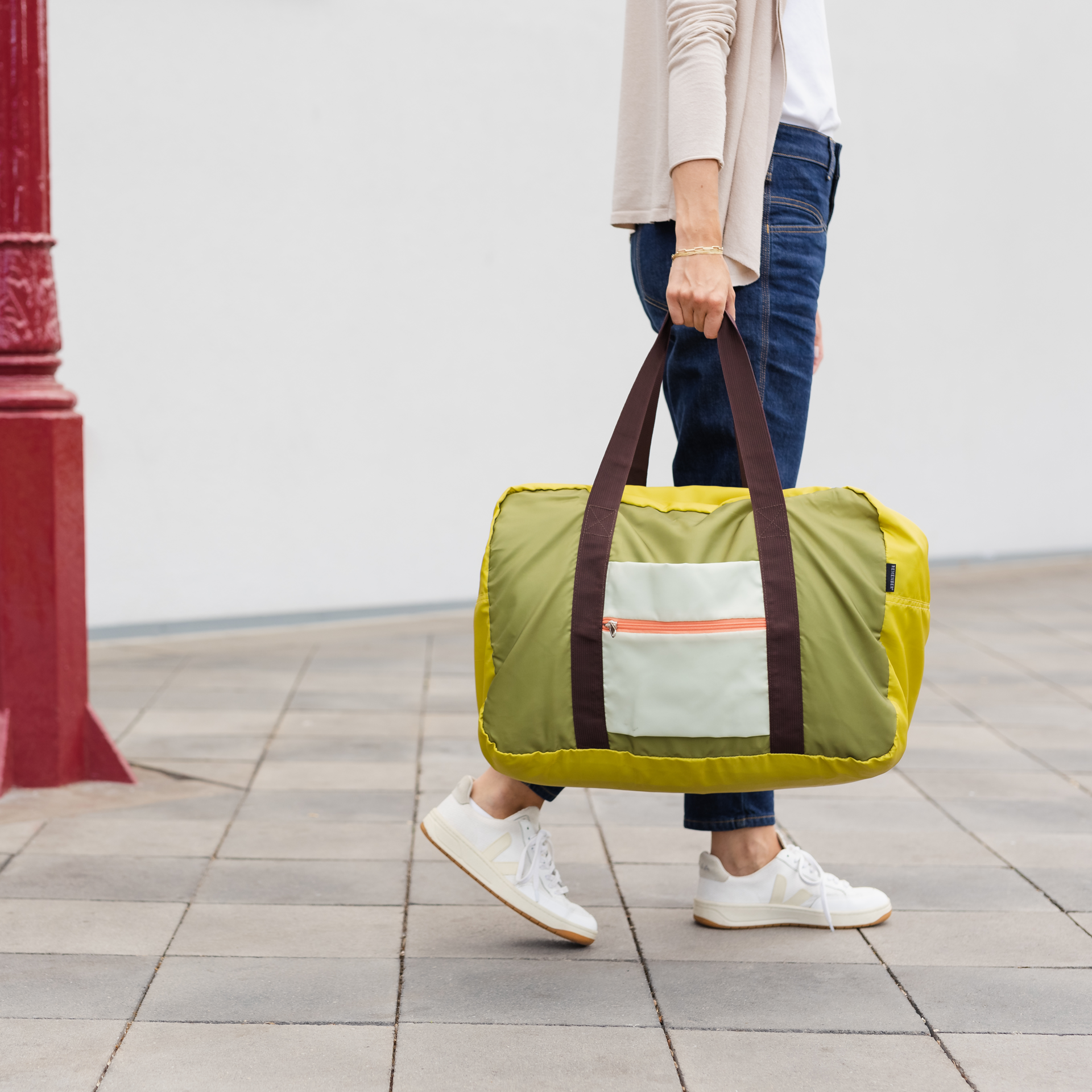 Freizeit-Reisetasche 'Liz' in Gelb und Olivgrün mit braunen Tragegriffen. Vorne befindet sich eine hellere Außentasche mit orangefarbenem Reißverschluss.